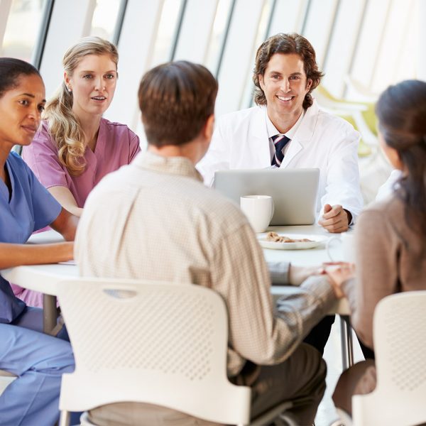 Group of medical professionals talking to a 2 patients